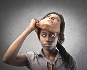 African young woman taking off a mask of a caucasian woman