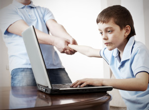 Father dragging son from the computer. Parent pulling child from