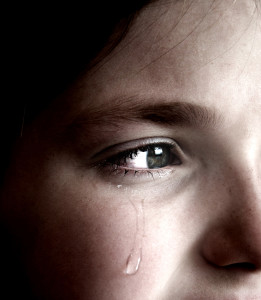 Closeup of girl crying with tear rolling down her cheek